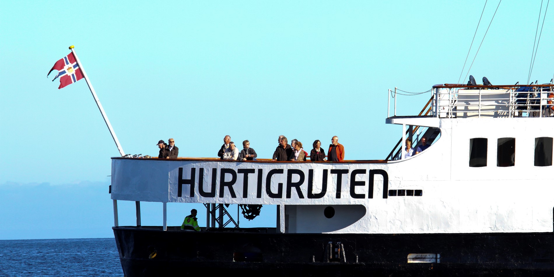 Le MS Nordstjernen, notre navire blanc et noir, navigue avec son pavillon flottant au vent. À la poupe, des passagers admirent la vue