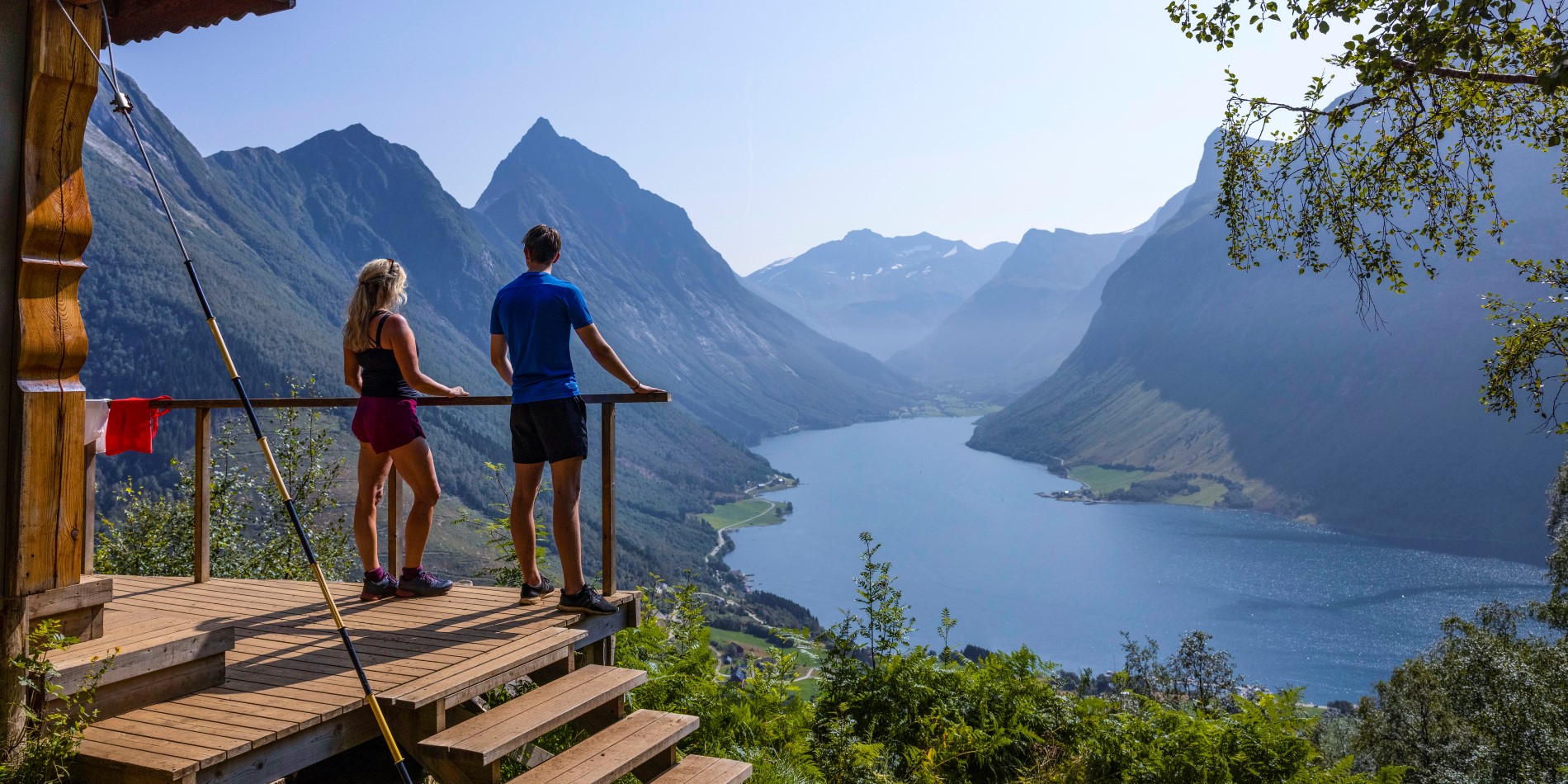 Un couple se tient debout sur un point de vue surplombant le Hjørundfjord. Vestcoast, Norvège