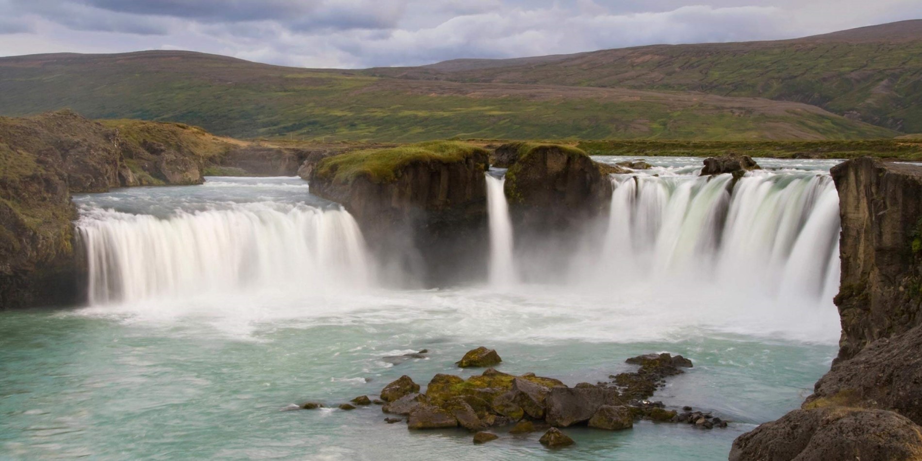 A large waterfall over a body of water with Aldeyjarfoss in the background