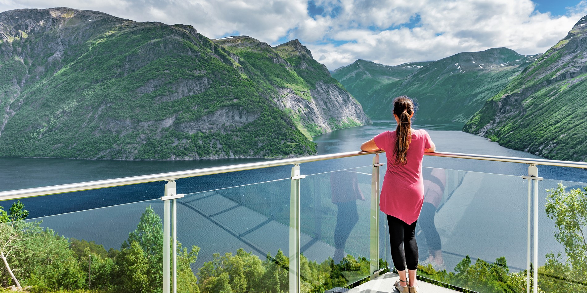 Woman standing on a balcony enjoying the view over the Sunnmøre Alps