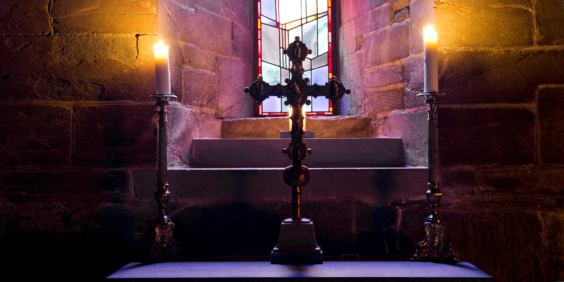Les trésors cachés de la cathédrale de Nidaros. L’image montre une croix et deux bougies allumées à l’intérieur de la cathédrale de Nidaros