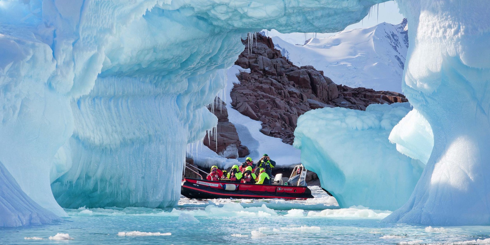Groupe de touristes dans le petit bateau parmi les formations spectaculaires de glace
